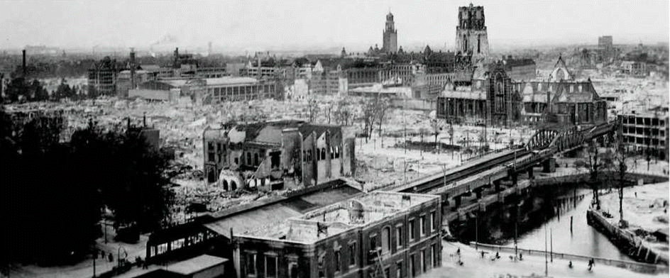rechts de ingang van de verwoeste Diergaarde en verder restanten van huizen en gebouwen als gevolg van het Duitse bombardement van 14 mei 1940, is het centrum van de stad verwoest. Gezien vanaf het Stationsplein,